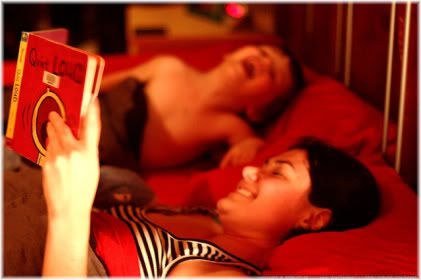 two children reading book in bed