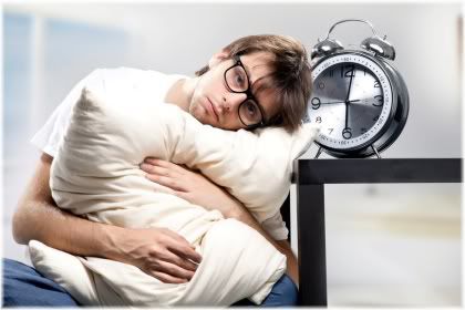 man holding pillow next to alarm clock