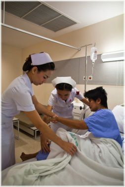 nurses with patients in hospital bed